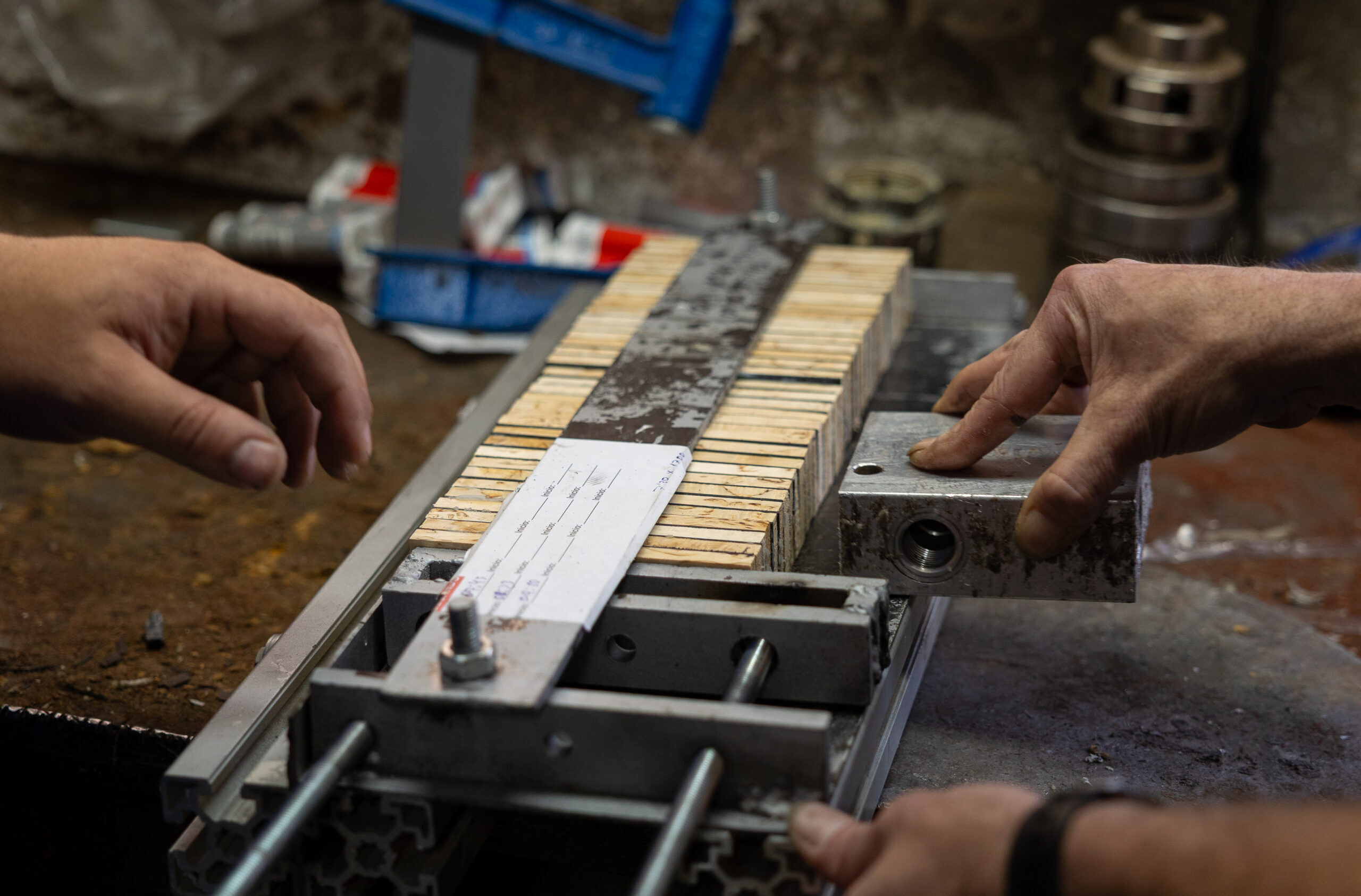 Workers manually pressing pieces of natural wood to make handles