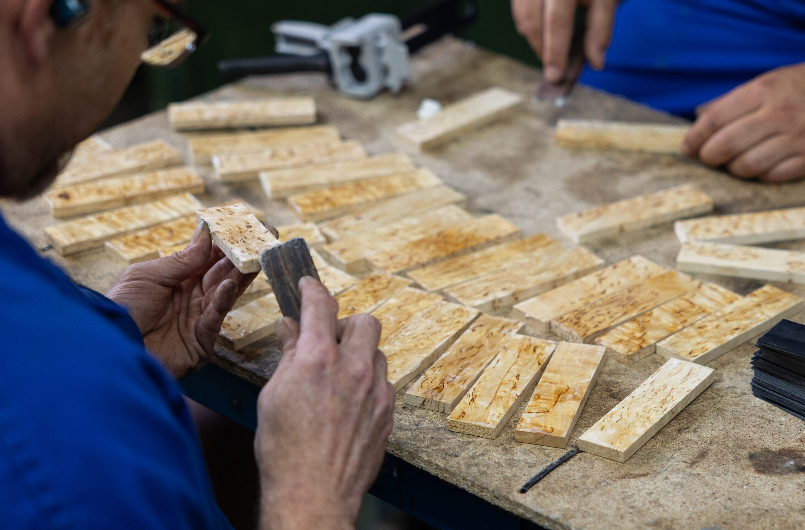 Workers manually assembling natural wood pieces for handles
