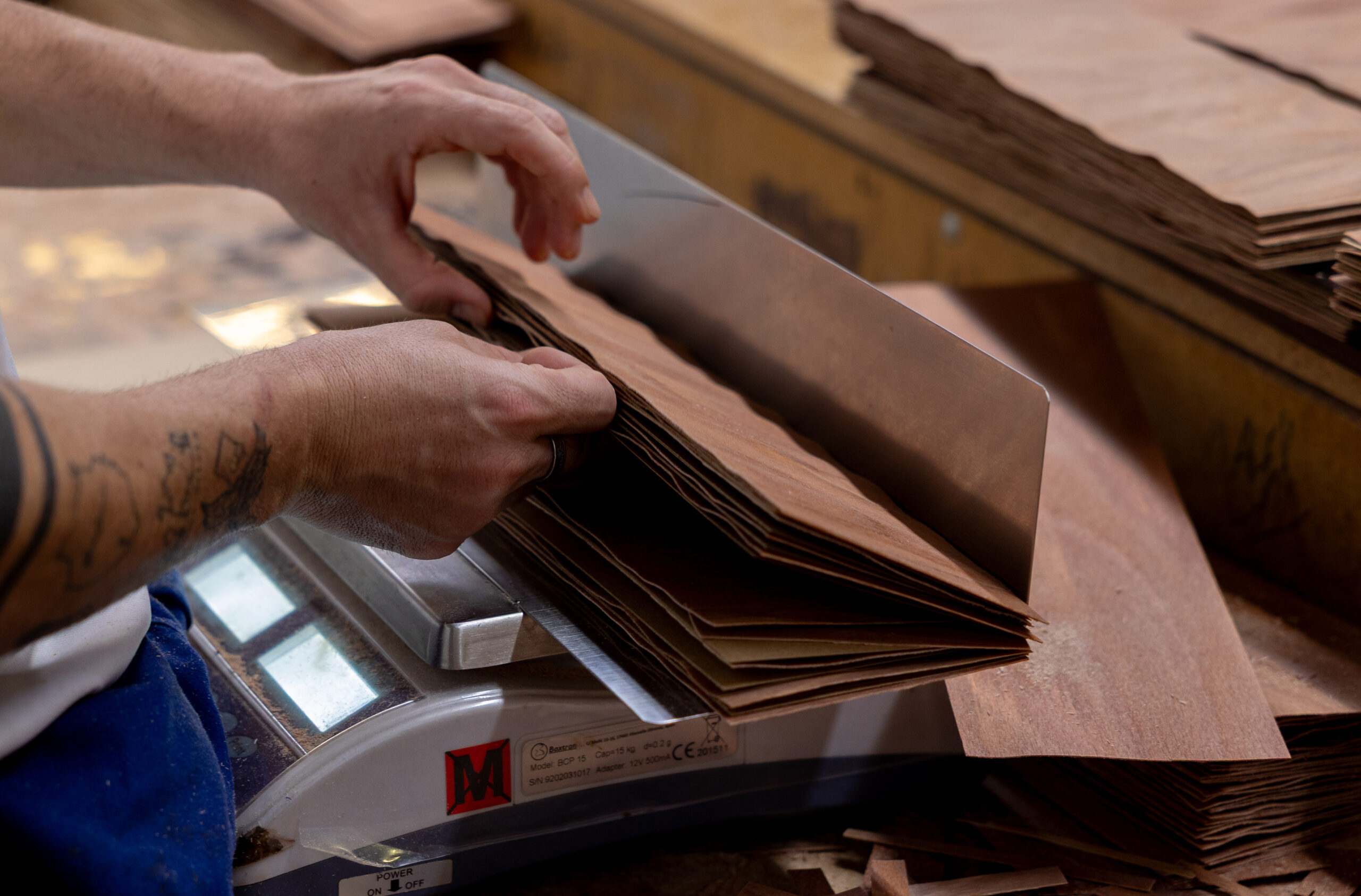 Factory worker weighing and handling laminated wood sheets